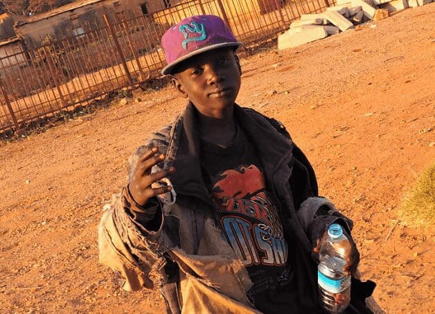 A man holding onto some water bottles in the dirt.