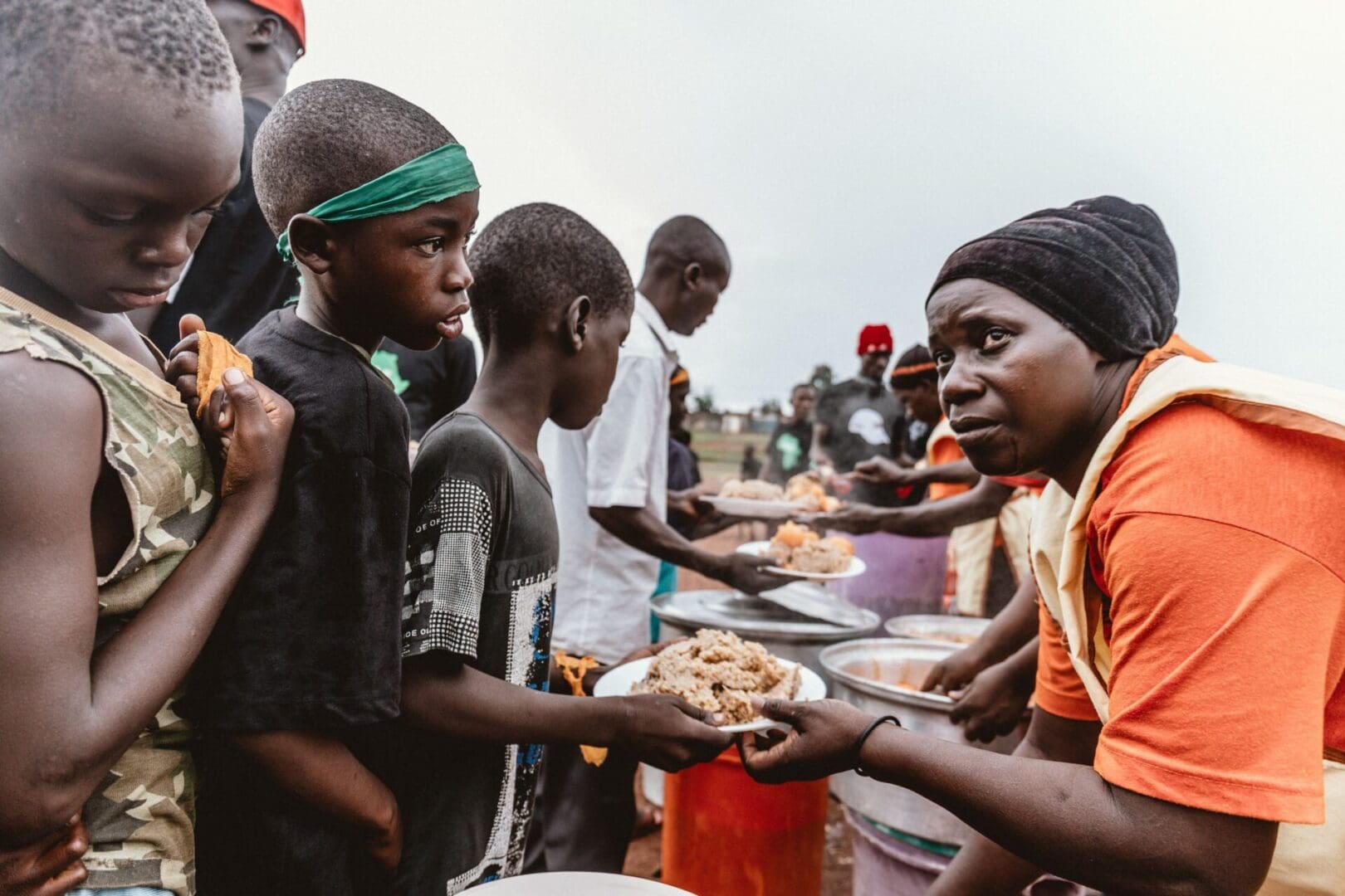 A group of people standing around plates with food.