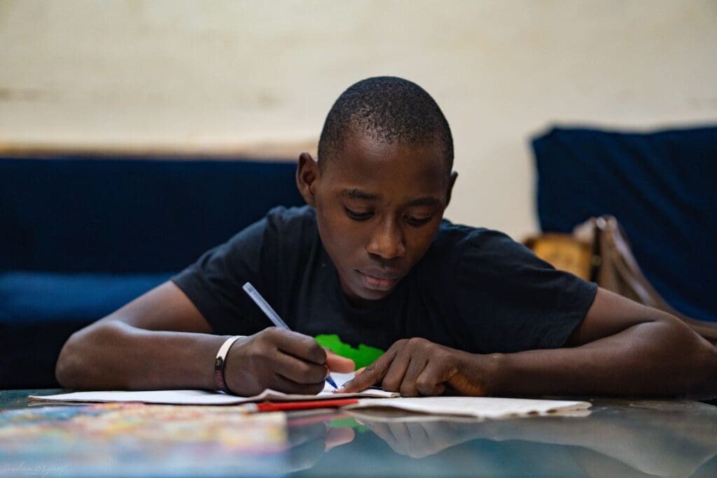 A boy is writing on paper at the table