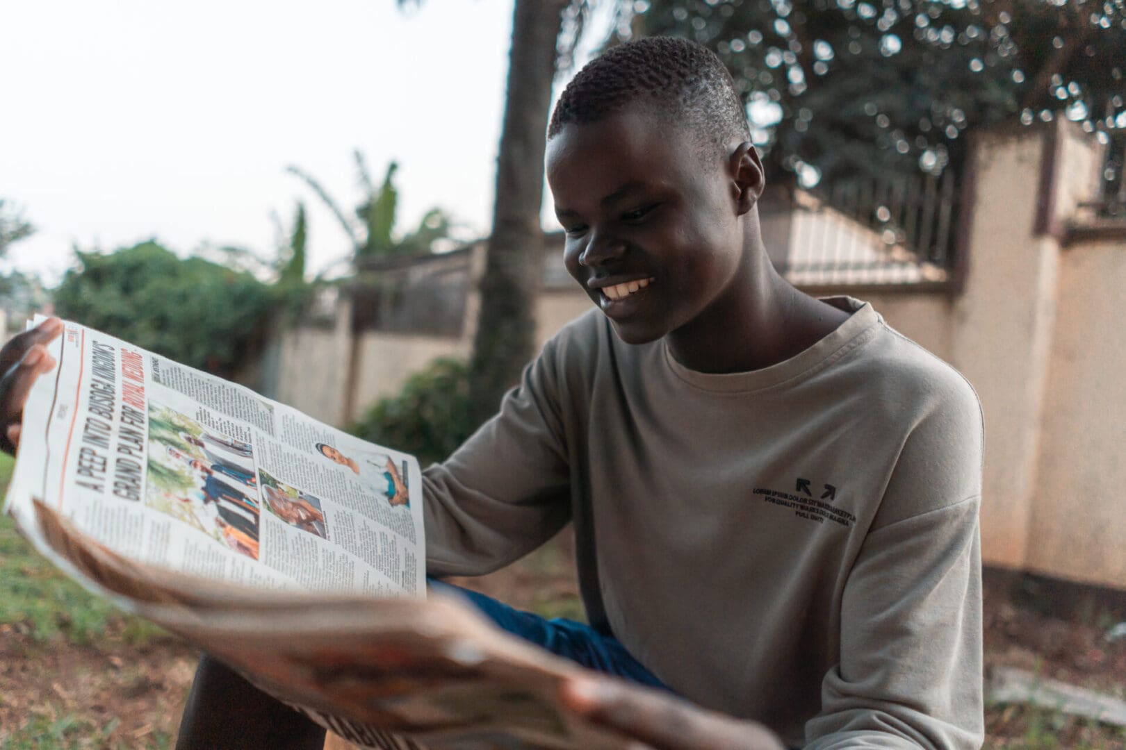 Man smiling while reading a newspaper.