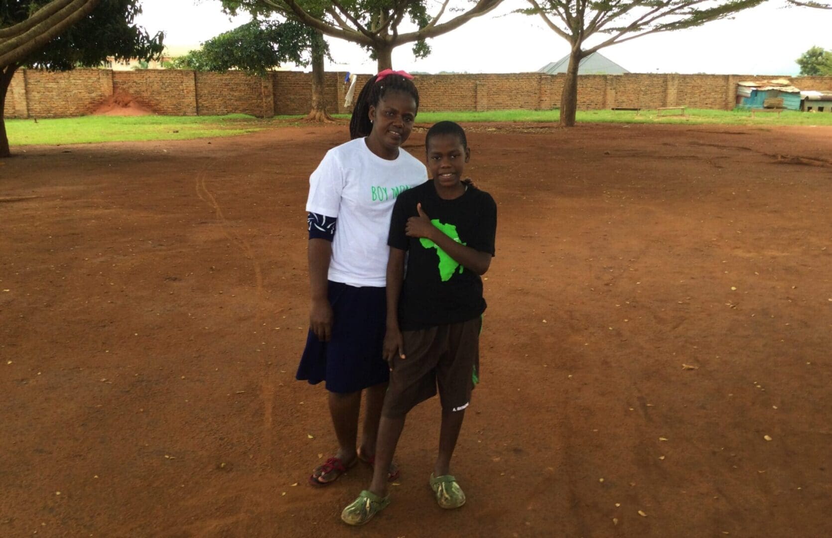 Two people standing on dirt ground.